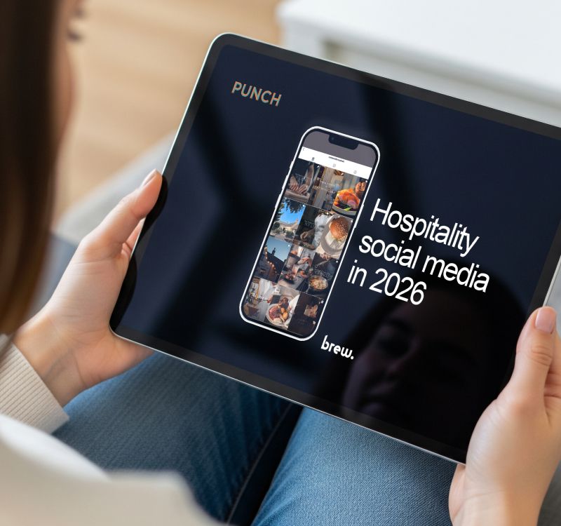 A photo of a seated person holding a tablet in their lap. The tablet displays the front cover of a social media training for pubs guide, which reads “Hospitality social media in 2026”.